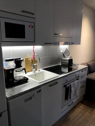 a white kitchen with a sink and a microwave at Moderni yksiö huippu sijainnilla in Jyväskylä