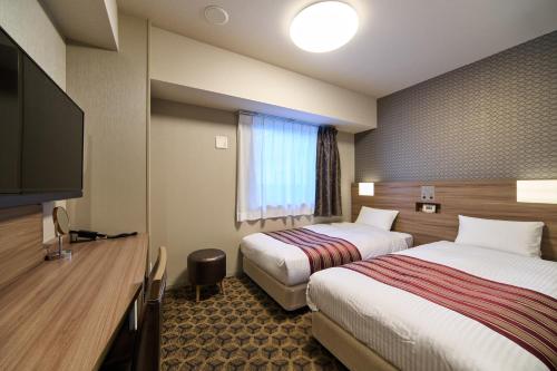 a hotel room with two beds and a flat screen tv at Hotel WBF Namba Motomachi in Osaka