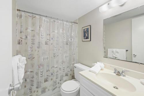 a white bathroom with a toilet and a sink at Quaint condo steps to the beach and dining in Marco Island