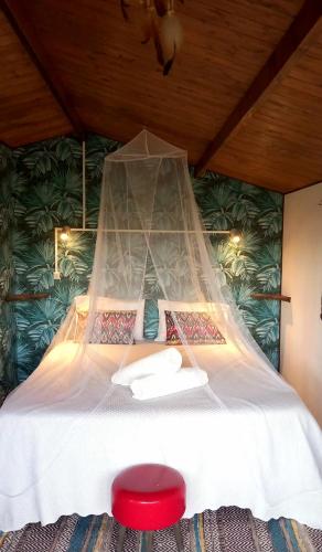 a bed with a mosquito net above it with a red stool at Casa do Sobreiro 2 in Serra das Alhadas