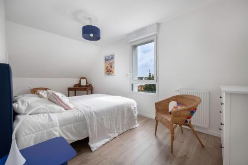 een witte slaapkamer met een bed en een stoel bij Appartement moderne pour 4 a La Baule in La Baule