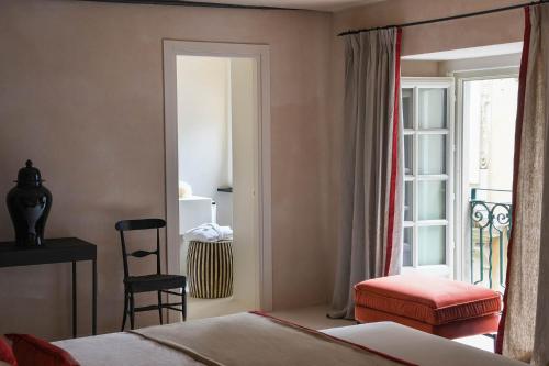 a bedroom with a bed and a chair and a window at Hotel Palazzo Durazzo Suites in Genova
