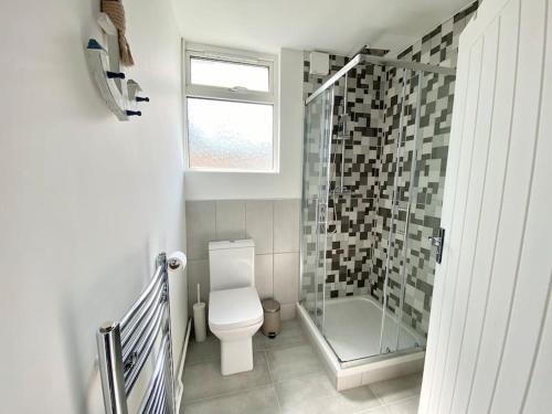 a bathroom with a toilet and a glass shower at Charming Seaside Cottage in Leigh-on-Sea in Southend-on-Sea