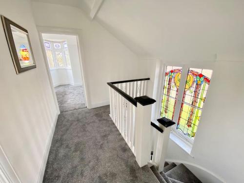 a hallway with a staircase with a stained glass window at Charming Seaside Cottage in Leigh-on-Sea in Southend-on-Sea