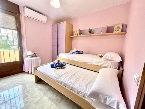 2 łóżka w pokoju z różowymi ścianami w obiekcie Arenda Clara villa con piscina privada al lado de la playa w mieście Hospitalet de l'Infant