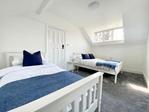 a white bedroom with two beds and a window at Charming Seaside Cottage in Leigh-on-Sea in Southend-on-Sea