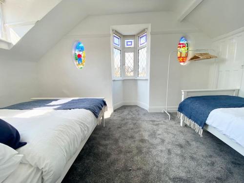 a bedroom with two beds and two windows at Charming Seaside Cottage in Leigh-on-Sea in Southend-on-Sea