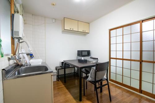a small kitchen with a sink and a table at Osaka U-Shuku in Osaka