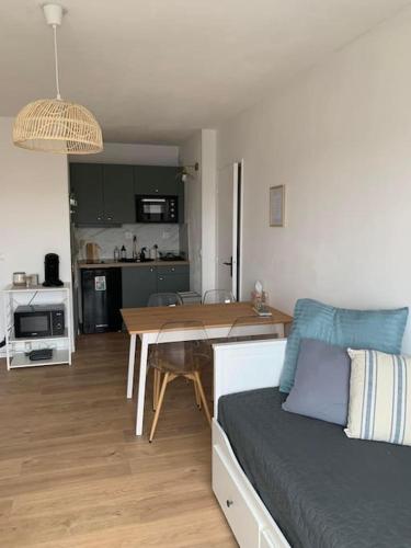 un salon et une cuisine avec un canapé et une table dans l'établissement Appartement T2 - 50m de la Mer - Parking - Wifi, à Courseulles-sur-Mer