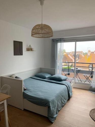 une chambre avec un lit et une grande fenêtre dans l'établissement Appartement T2 - 50m de la Mer - Parking - Wifi, à Courseulles-sur-Mer