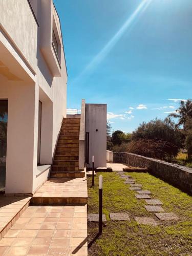 a white building with stairs and a stair case at PetraSicula Apartment in Acitrezza
