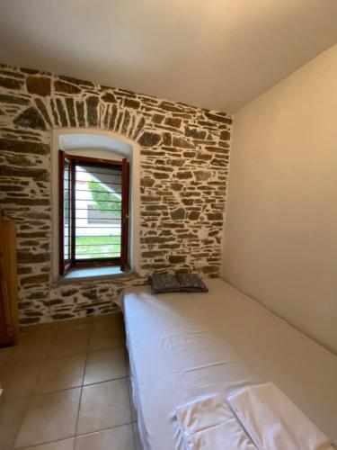 1 dormitorio con pared de ladrillo y 1 cama con ventana en Petrino en Agios Nikolaos