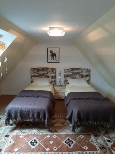 a attic room with two beds and a rug at TY KOANT in Daoulas