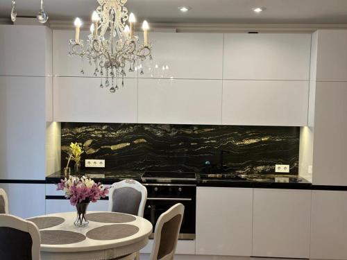 eine Küche mit einem Tisch mit Stühlen und einem Kronleuchter in der Unterkunft BIRUTE AVENUE 2 BEDROOMS in Palanga