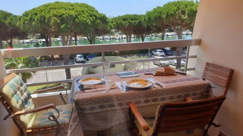 una mesa con platos de comida en el balcón en Studio Cabine - Port Camargue - Bord de Mer, en Le Grau-du-Roi