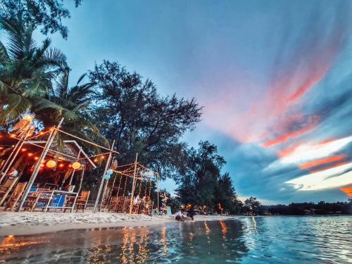 a beach with a group of people sitting on the sand at Kirati Beach Resort in Choeng Mon Beach