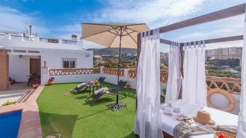 a balcony with a lawn and an umbrella at Villa Naiara Torrox by Ruralidays in Torrox