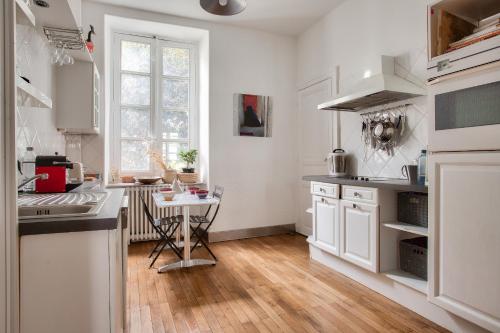 une cuisine avec des armoires blanches et une table à l'intérieur dans l'établissement Échappée nantaise pour 4 personnes, à Nantes