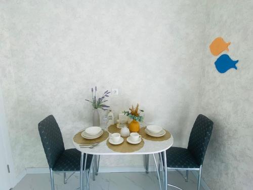 a dining room table with chairs and a white table with plates and bowls at Гранд Чемпион in Astana