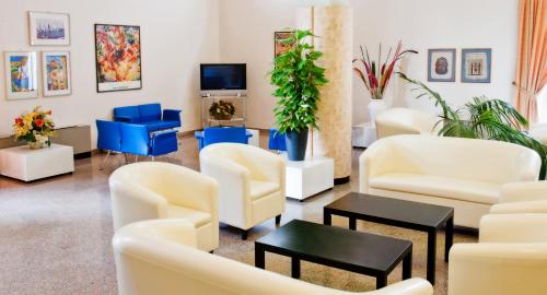 a waiting room with white chairs and a tv at Hotel Garden B&B in Marotta