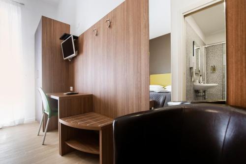 a hotel room with a chair and a desk and a bedroom at Gu Hotel in Guidonia