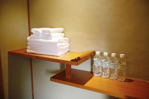 a shelf with a stack of towels and bottles of water at 湯布院我楽珍民泊Yufuin Garakuchin in Yufuin
