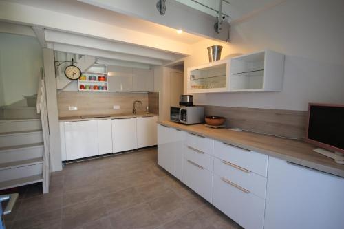 Il comprend une cuisine avec des placards blancs et une télévision. dans l'établissement Jolie maison de vacances rénovée et climatisée, 5 couchages, 2 chambres et mezzanine, 100m de la plage, residence LE VILLAGE DE LA MER LRVM39, à Portiragnes