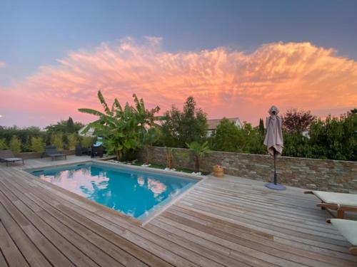 a swimming pool on a wooden deck with an umbrella at Villa T4 avec piscine in Lucciana