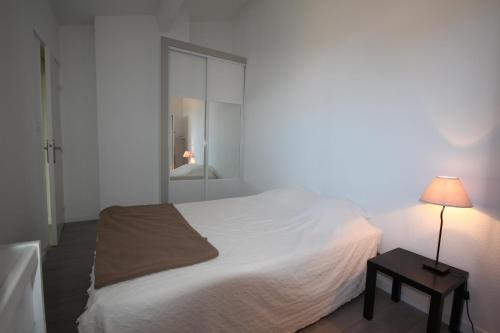 - une chambre avec un lit blanc et une table avec une lampe dans l'établissement Jolie maison de vacances rénovée et climatisée, 5 couchages, 2 chambres et mezzanine, 100m de la plage, residence LE VILLAGE DE LA MER LRVM39, à Portiragnes