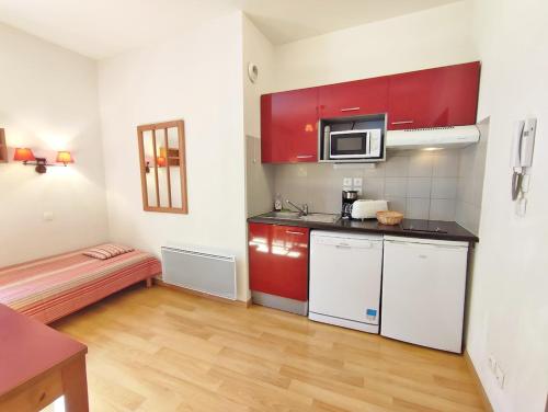 Habitación pequeña con cocina con armarios rojos. en Frimousse, Studio, wifi, centre Luchon, casier à skis, 3 personnes, en Luchon
