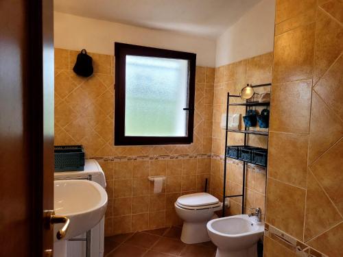 een badkamer met een toilet, een wastafel en een raam bij SAS DOMOS De BADDE MANNA in Torpè