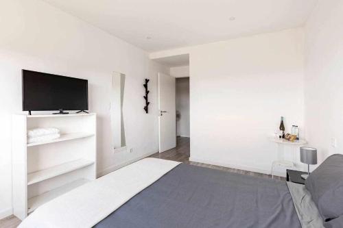 a white living room with a flat screen tv at Bossa Nova GuestHouse in Braga