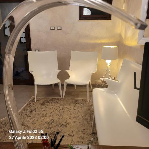 a room with two white chairs and a mirror at Raggi di Sole in Custonaci