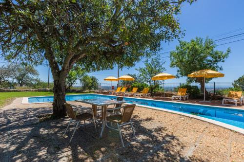 a table and chairs under a tree next to a pool at Vila Limão in Boliqueime