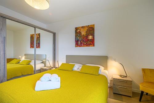 1 dormitorio con 2 camas amarillas y espejo en L'Audacieux - Appt neuf avec vue sur les toits, en Vannes