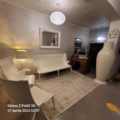 a living room with white chairs and a table and a vase at Raggi di Sole in Custonaci