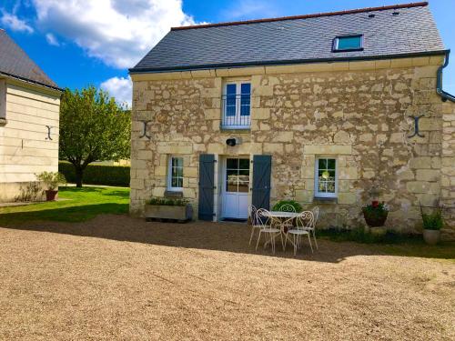 una casa in pietra con un tavolo e sedie di fronte di La Grange de l'Olive a Chinon