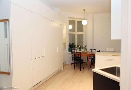 uma cozinha com armários brancos e uma mesa com cadeiras em Corner apartment em Helsinque