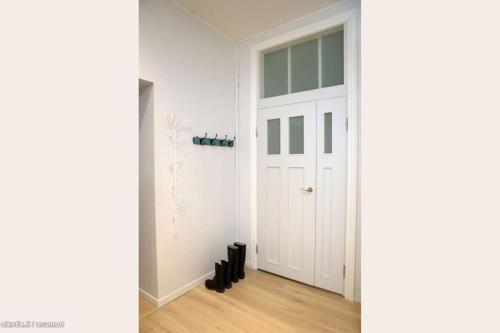 einen Flur mit einer weißen Tür und schwarzen Schuhen in der Unterkunft Corner apartment in Helsinki