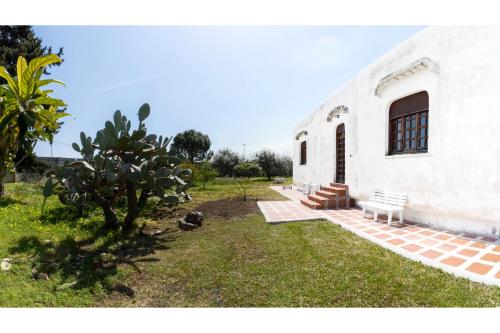 un edificio blanco con un banco y un árbol en Le Verdi Dimore, en Lecce