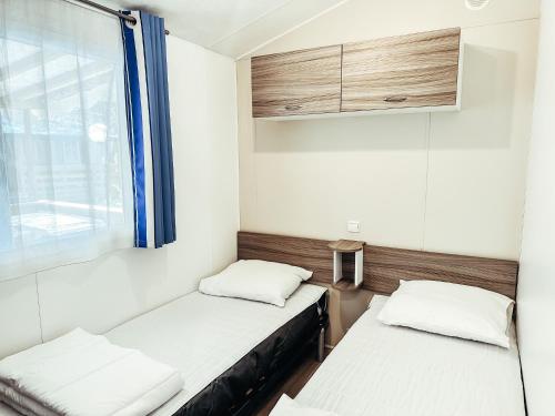 deux lits dans une petite pièce avec une fenêtre dans l'établissement 3 bedroom Chalets Camping Leï Suves - JoyCasa, à Roquebrune-sur Argens