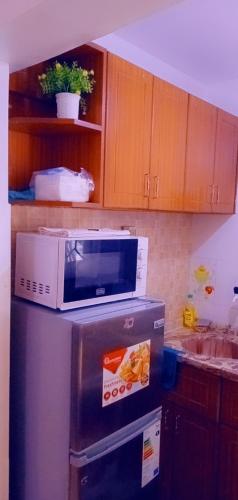 a microwave on top of a refrigerator in a kitchen at Lux Suites Vee studio Apartments Bamburi in Bamburi