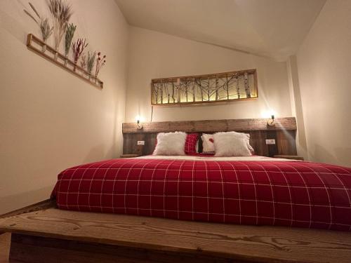a bedroom with a large bed with a red blanket at Hotel Le Clou in Arvier