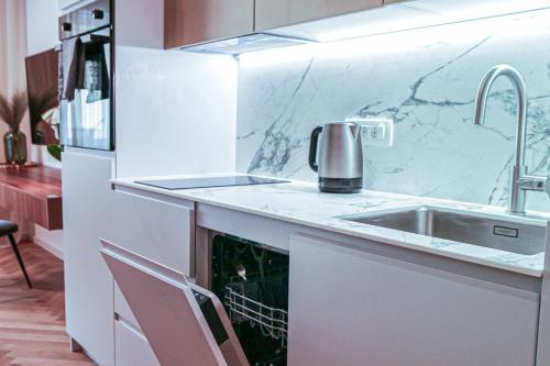 a white kitchen with a sink and a counter top at JU3 Apartments in Ljubljana