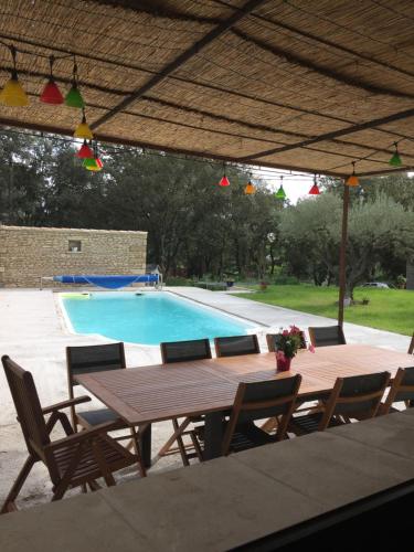- une table et des chaises en bois à côté de la piscine dans l'établissement Provençal bastide in Uzès, à Uzès