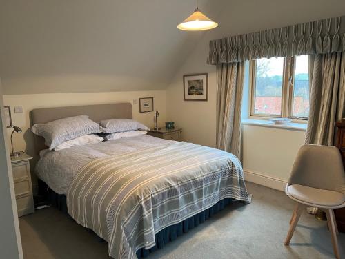 um quarto com uma cama, uma cadeira e uma janela em The Norfolk Haybarn em Sedgeford