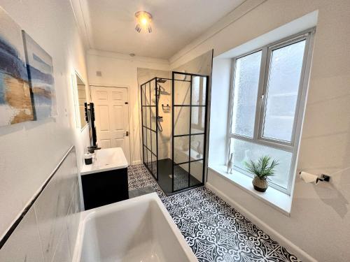 La salle de bains est pourvue d'une baignoire, d'un lavabo et d'une fenêtre. dans l'établissement Large house on the edge of the Brecon Beacons, à Beaufort