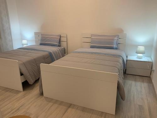 2 camas en una habitación pequeña con 2 lámparas en La Fortuna en Quiliano