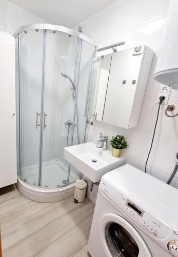 a white bathroom with a shower and a washing machine at Sea view App Mirta in Umag