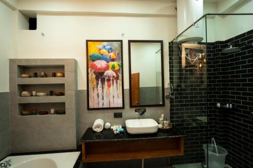 baño con lavabo y una pintura de sombrillas en Barefoot Homestays, en Rāmnagar